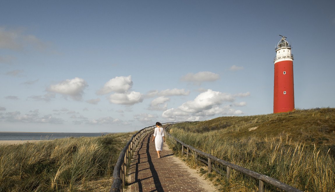 Vrouw loopt over pad bij vuurtoren van Texel in de zomer Vrouw loopt over pad bij vuurtoren van Texel in de zomer