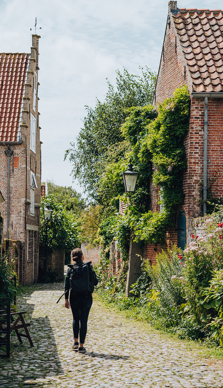 Vrouw wandelt door een groene straat in het Zeeuwse stadje Veere Vrouw wandelt door een groene straat in het Zeeuwse stadje Veere
