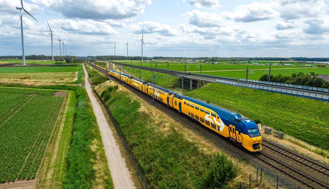NS-trein rijdt door Nederlands landschap met windmolens NS-trein rijdt door Nederlands landschap met windmolens